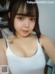 A woman in a white tank top posing for a picture.