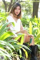 A woman sitting in the middle of a lush green garden.