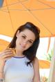 A woman holding a sandwich under an umbrella.