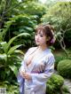 A woman in a kimono posing for a picture in a garden.