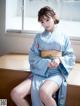 A woman in a blue kimono sitting on a wooden table.