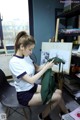 A woman sitting on a chair in front of a painting.