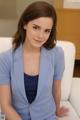 A woman in a blue suit sitting on a white couch.