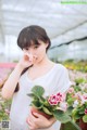 A woman holding a potted plant in a greenhouse.