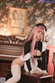 A woman with pink hair sitting on a piano.