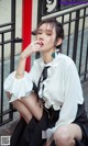 a woman sitting on the ground next to a fence