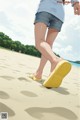 A woman walking on a sandy beach with her feet in the sand.