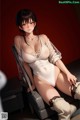 A woman in a white bodysuit sitting on a chair.