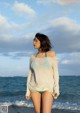 A woman standing on a beach next to the ocean.