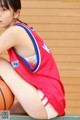 A woman sitting on a bench with a basketball.