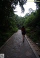 A woman walking down a stone path in the woods.