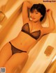 A woman in a black lingerie laying in a bathtub.