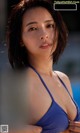 A woman in a blue bikini posing by a pool.